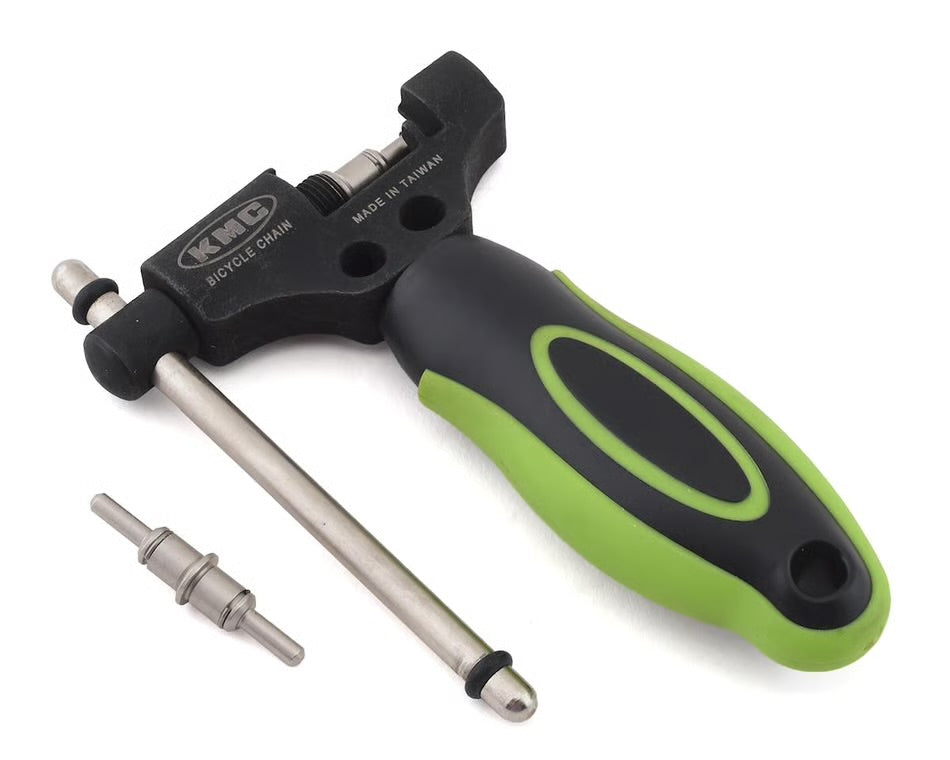KMC reversible chain tool with a black and green ergonomic handle, metal breaker pin, and spare pin on a white background.