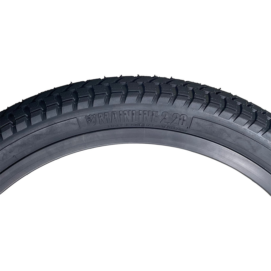 Black S&M Mainline 20-inch BMX tire with directional tread and micro-knurled surface texture.
