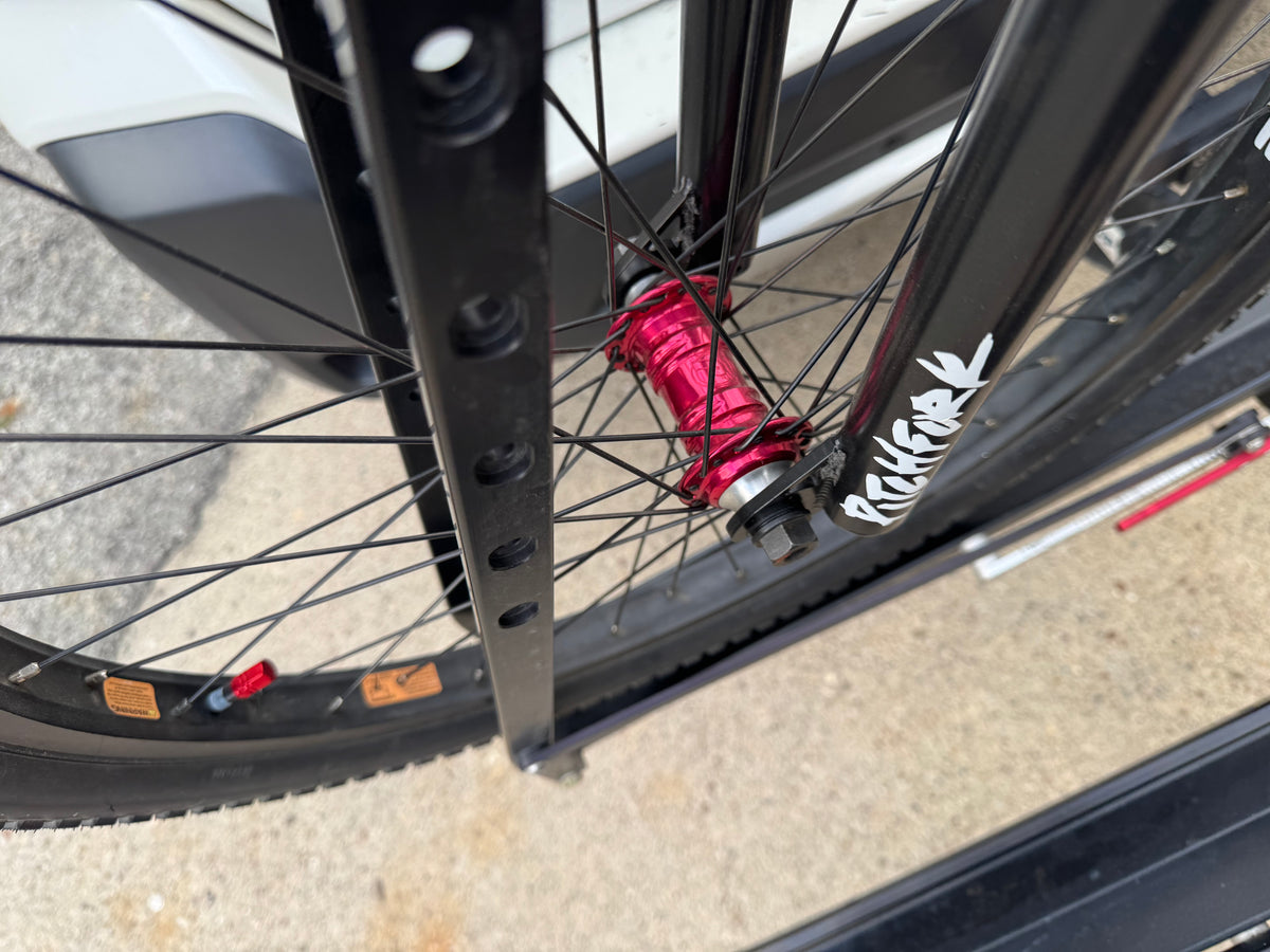 Close-up of S&M BMX bike featuring a bright red Profile hub, black forks, and black rims mounted on a bike rack.