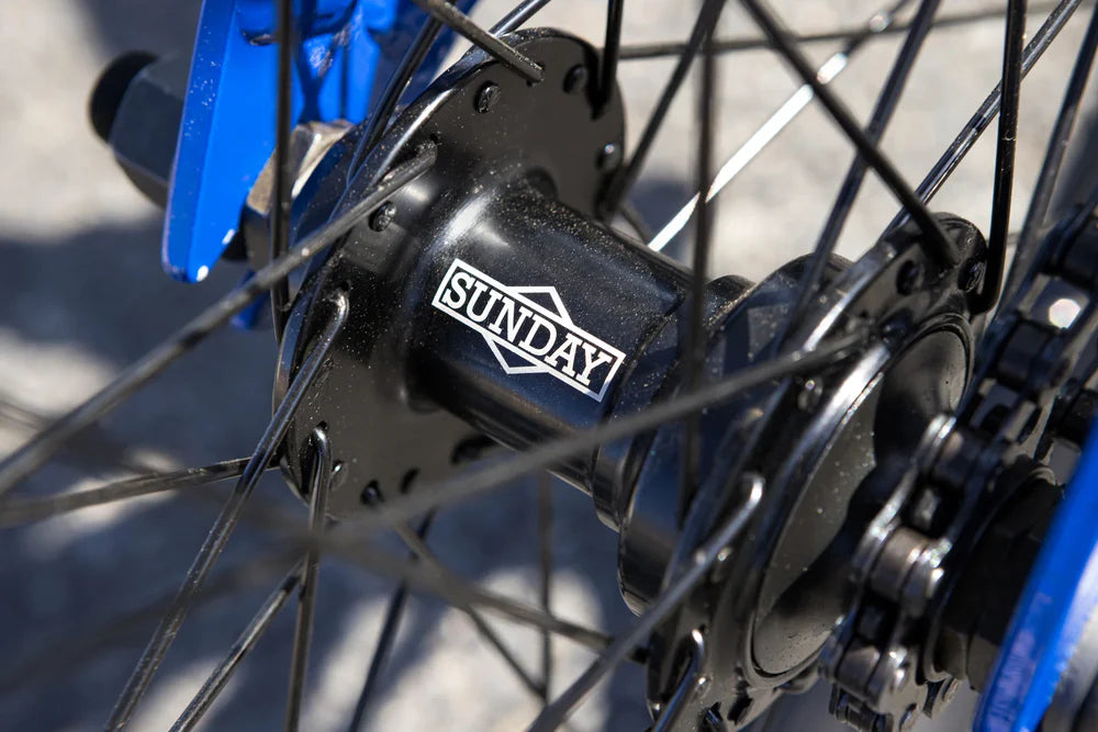 Black Sunday BMX bike hub with branded logo, black spokes, and glossy blue frame components.