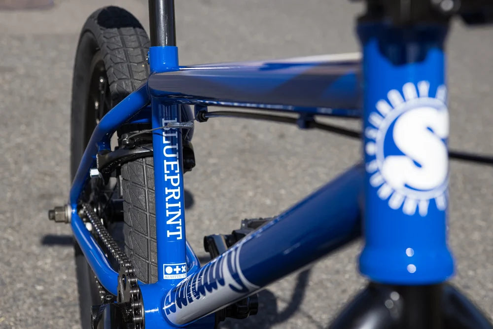 Gloss Sunday Blue BMX bike frame with Blueprint branding, integrated head tube, and black tires on a paved surface.