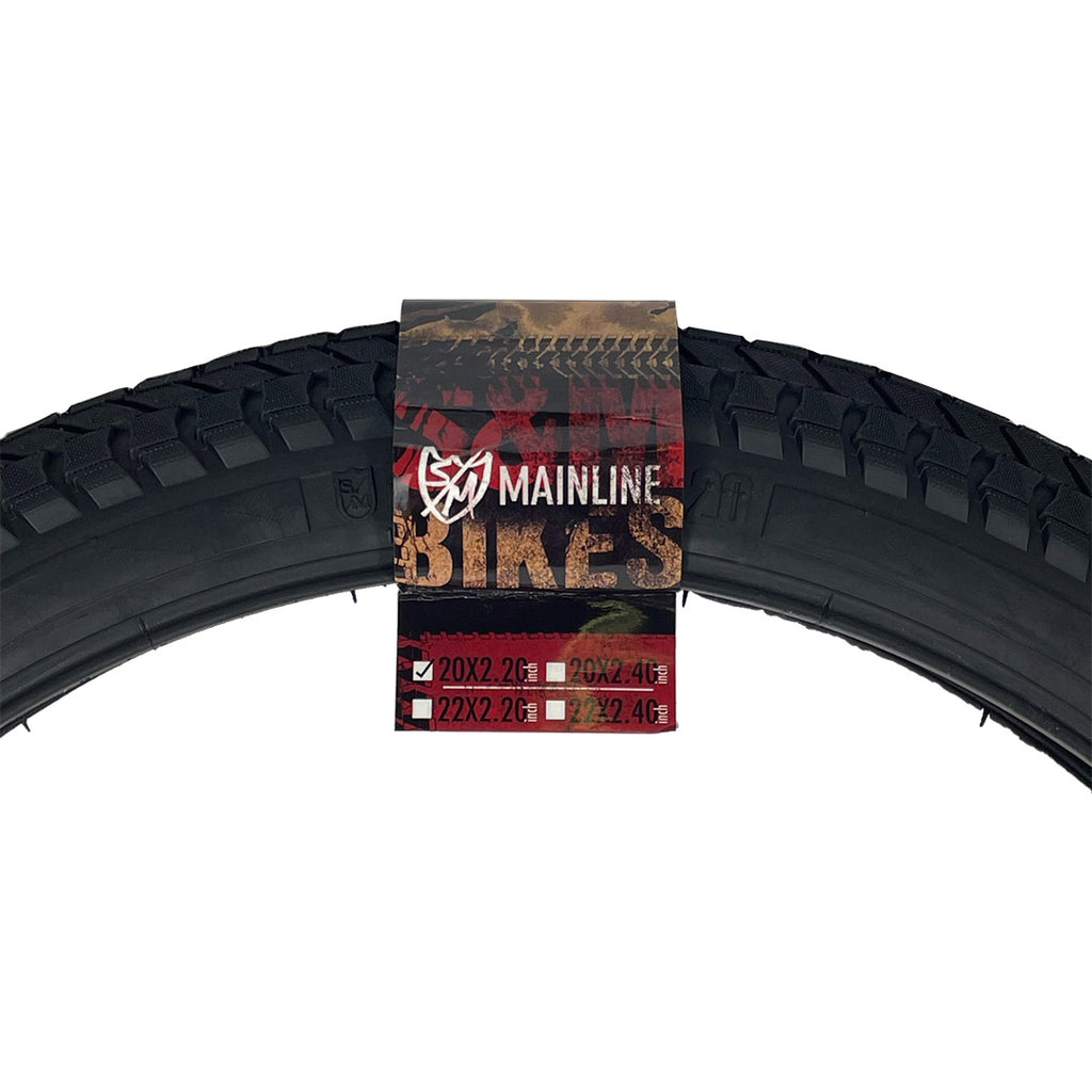 Black S&M Mainline 20-inch BMX tire with directional tread and branded paper label featuring size specifications.