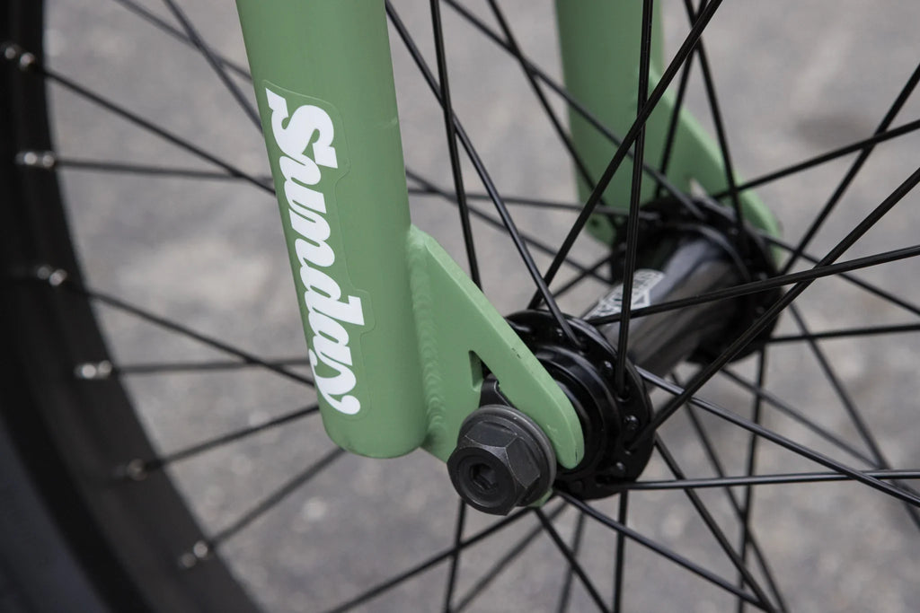 Matte sage green Sunday Forecaster BMX fork with black spokes and hub.